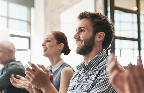 A happy group of people applaud their company's human resource management policies